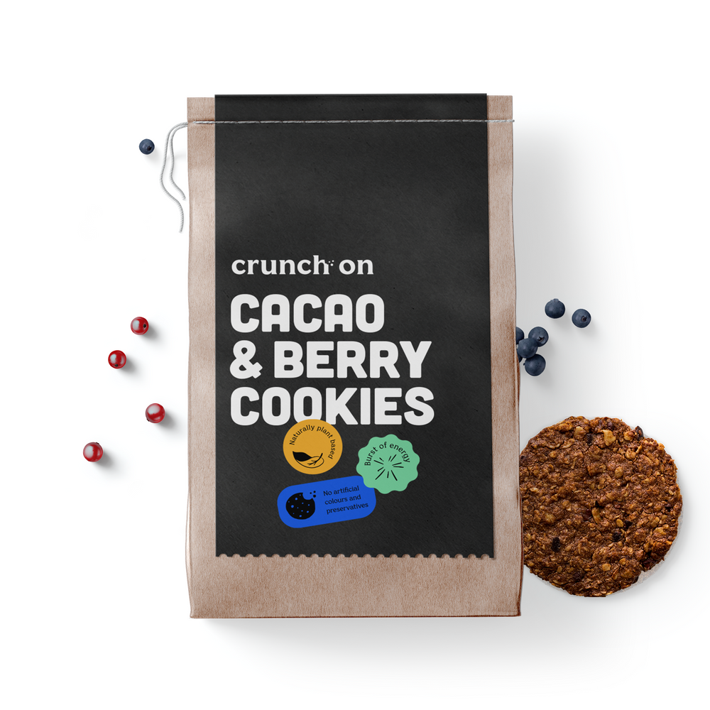 Front view of bag of Crunch On Cacao & Berry Cookies, with cookie and berries in the background