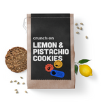 Front view of bag of Crunch On Lemon & Pistachio Cookies, with cookie, pistachio nuts and lemon in the background