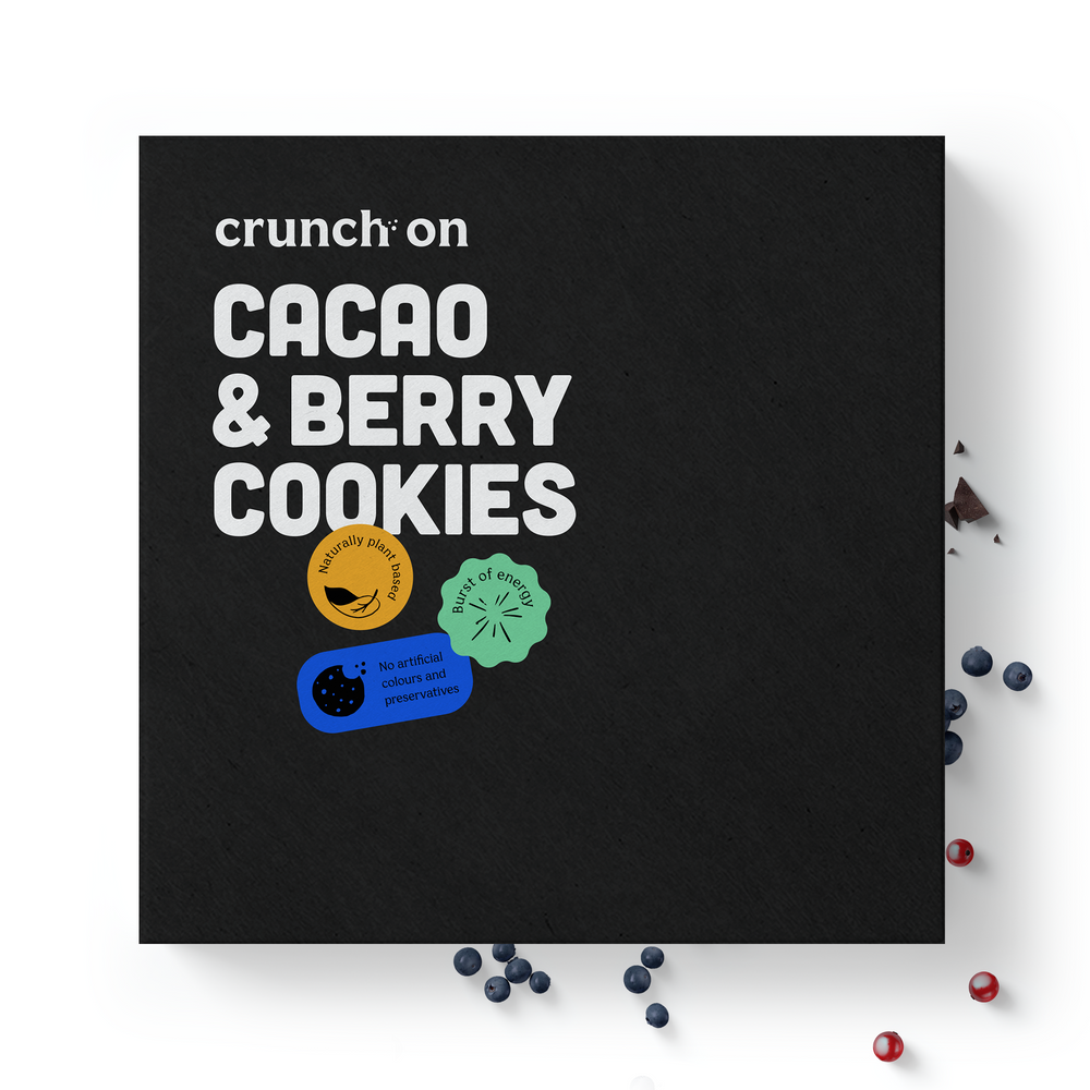 Front view of box of Crunch On Cacao & Berry Cookies, with chocolate and berries in the background