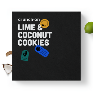 Front view of box of Crunch On Lime & Coconut Cookies, with coconut and lime in the background